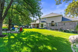 Rear view of property featuring a patio, a lawn, brick siding, and stucco siding