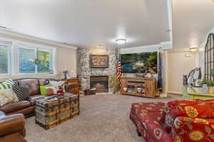 Living room featuring ornamental molding, a fireplace, carpet flooring, and a textured ceiling