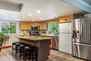 Kitchen featuring appliances with stainless steel finishes, dark stone counters, a breakfast bar area, a center island, and recessed lighting