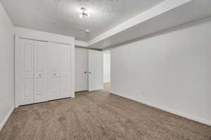 Unfurnished bedroom featuring carpet, a textured ceiling, and a closet