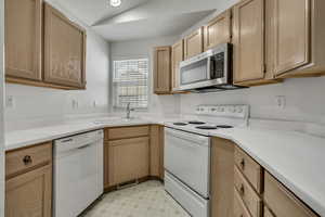 Kitchen featuring white appliances, light countertops, light brown cabinetry, and recessed lighting