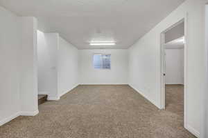 Spare room featuring carpet and a textured ceiling