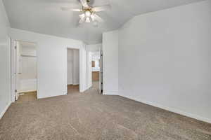 Unfurnished bedroom with ensuite bath, light carpet, a walk in closet, and ceiling fan