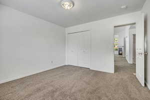 Unfurnished bedroom with carpet floors, a closet, a textured ceiling, and a glass covered fireplace