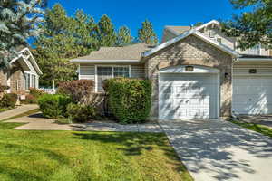 View of front of home featuring brick siding, driveway, a front yard, and an attached garage