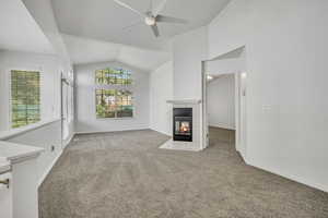 Unfurnished living room featuring carpet, a tile fireplace, a ceiling fan, and high vaulted ceiling