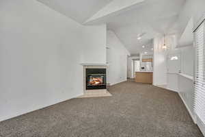 Unfurnished living room with light carpet, a fireplace, ceiling fan, and high vaulted ceiling