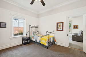 Bedroom featuring dark carpet, ceiling fan, and crown molding