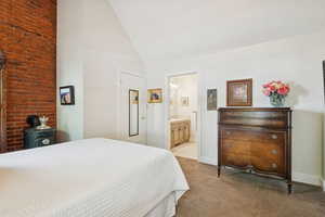 Bedroom featuring light colored carpet, high vaulted ceiling, and ensuite bath
