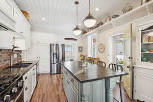 Kitchen featuring a breakfast bar, tasteful backsplash, recessed lighting, stainless steel appliances, and dark wood finished floors