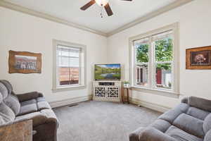 Living room with carpet floors, ornamental molding, and ceiling fan