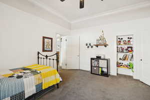 Carpeted bedroom featuring ornamental molding and a ceiling fan