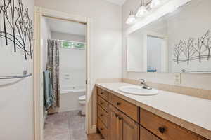 Bathroom with vanity, shower / bathtub combination with curtain, and light tile patterned floors