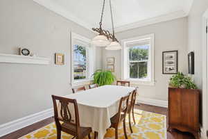 Dining area featuring dark wood-style floors and crown molding