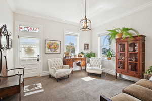 Living area featuring carpet, crown molding, and a chandelier