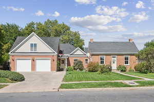 View of front of home featuring driveway, a front yard, brick siding, and a garage