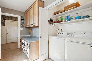 Laundry room featuring light tile patterned floors, a textured ceiling, and washing machine and clothes dryer
