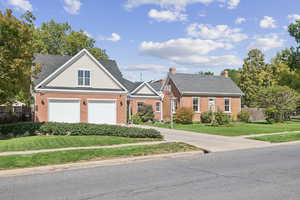 View of front of house with brick siding, driveway, a garage, a shingled roof, and a chimney