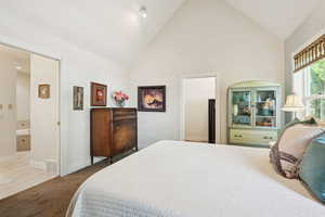Tiled bedroom featuring high vaulted ceiling, carpet flooring, and ensuite bath