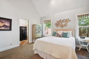 Bedroom with high vaulted ceiling, carpet floors, and connected bathroom