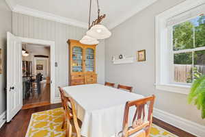 Dining space with ornamental molding, dark wood finished floors, and wooden walls