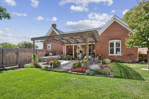 Rear view of property featuring a pergola, a patio, brick siding, and a chimney