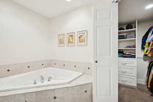 Bathroom featuring a bath, a walk in closet, and recessed lighting