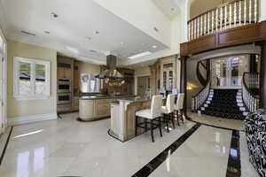 Kitchen featuring glass insert cabinets, a breakfast bar area, ornamental molding, dark stone counters, and french doors