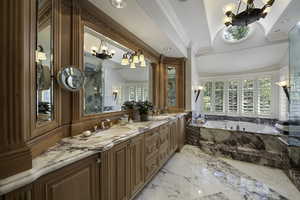 Bathroom with crown molding, a garden tub, double vanity, a chandelier, and light marble finish floors