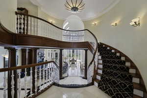 Staircase featuring tile patterned flooring, ornamental molding, and a towering ceiling
