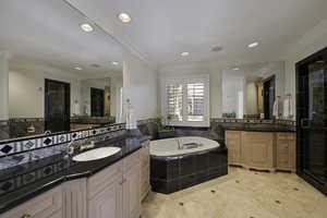 Bathroom with ornamental molding, a stall shower, a garden tub, two vanities, and recessed lighting