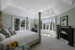 Bedroom with a tray ceiling, carpet, ornamental molding, a fireplace, and recessed lighting