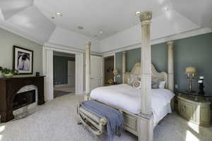 Carpeted bedroom with a tray ceiling, crown molding, a fireplace, and recessed lighting