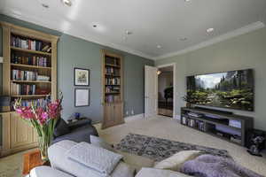Carpeted living area with crown molding and recessed lighting