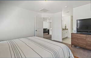 Bedroom with light carpet, light tile patterned floors, and ensuite bathroom