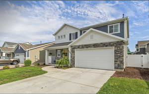 Traditional home with concrete driveway, covered porch, a garage, stone siding, and a gate