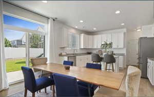 Dining room with light wood finished floors and recessed lighting
