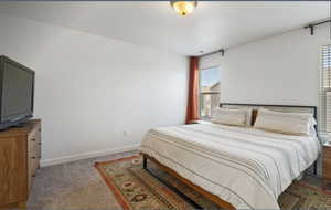 Bedroom featuring light carpet and baseboards