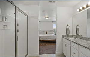 Full bathroom featuring vanity, light tile patterned floors, a shower stall, and ensuite bathroom