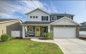 View of front of house with covered porch, a gate, concrete driveway, stone siding, and a garage
