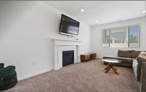 Living area with a glass covered fireplace, carpet, and recessed lighting