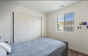 Bedroom with dark carpet and a closet