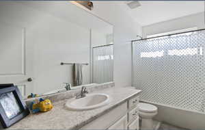 Full bath with vanity, shower / bath combo with shower curtain, and tile patterned floors
