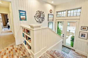 Entrance foyer featuring wood walls, french doors, brick flooring, and recessed lighting