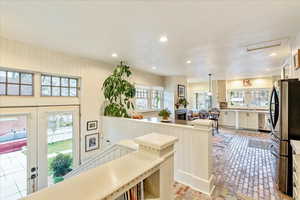 Kitchen with brick flooring, appliances with stainless steel finishes, decorative light fixtures, recessed lighting, and wooden walls
