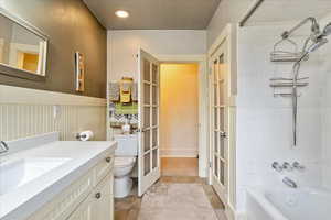 Full bathroom featuring bathing tub / shower combination, vanity, french doors, light tile patterned floors, and recessed lighting