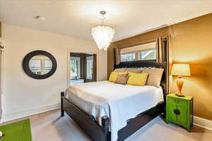 Carpeted bedroom featuring multiple windows and a chandelier