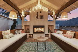 Living room featuring wooden walls, a large fireplace, beamed ceiling, and high vaulted ceiling