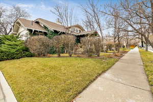 View of front of home with a front lawn, a chimney, and roof with shingles