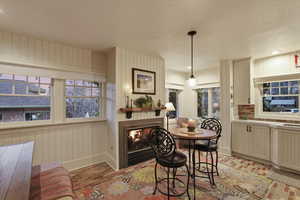 Dining area with a glass covered fireplace and wood walls